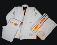 Load image into Gallery viewer, A set of white Brazilian jiu-jitsu gi with lotus flower embroidery, including a jacket and pants, along with a gi bag on a black background.